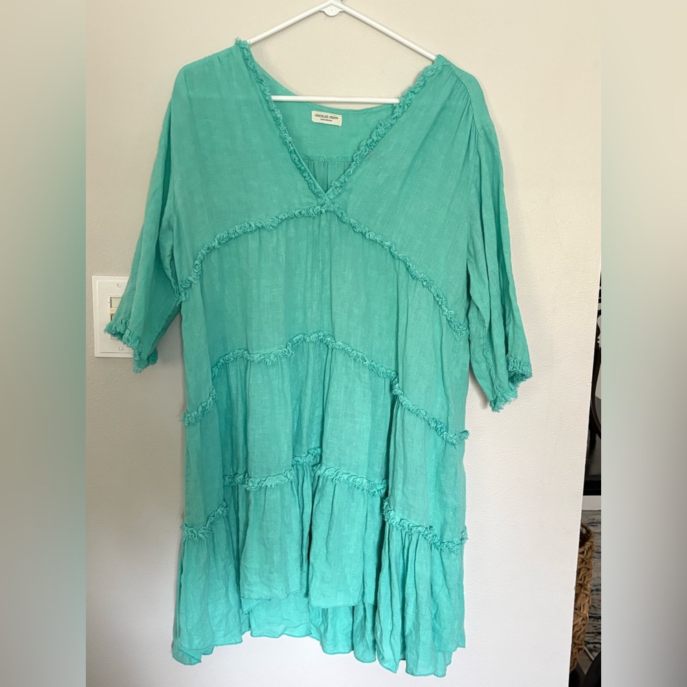 Preppy teal linen tunic dress features a V-neckline and tiered ruffle details.